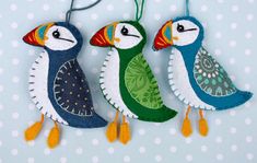 three colorful birds hanging from strings on a polka dot background