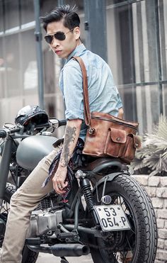 a man sitting on the back of a motorcycle with a bag strapped to it's seat