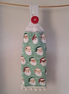 a green santa clause christmas stocking hanging on a clothes line with a red button