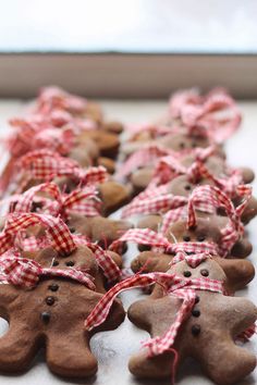 some very cute looking gingerbread men on a white counter top with red and white checkered ribbon