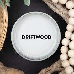 the word driftwood written in black on a white plate surrounded by beads and branches