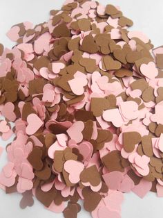 pink and brown heart shaped confetti on a white table with lots of hearts