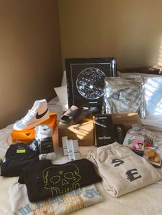 an assortment of items are laid out on the bed, including shoes and t - shirts