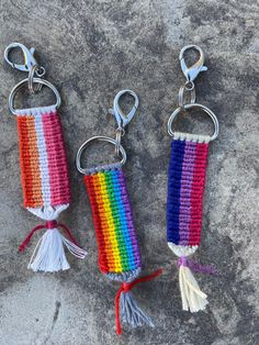 three crocheted keychains with tassels on them sitting on a rock