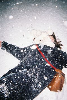 a woman laying in the snow with her arms out