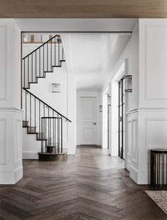 an empty hallway with wooden floors and white walls