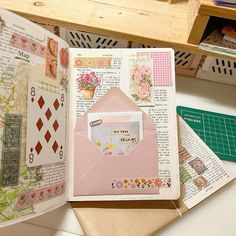 an open book sitting on top of a table filled with papers and other crafting supplies