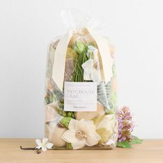 a bag filled with lots of flowers sitting on top of a wooden table