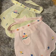 three baby bibs laying on the floor next to each other, one with flowers