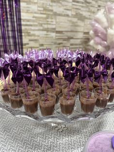 desserts are arranged on a glass platter with purple ribbons