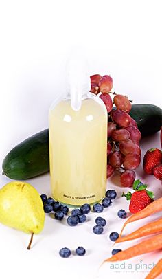 a bottle of liquid surrounded by fruits and vegetables