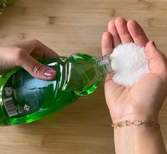 a person holding a bottle of green liquid and some white stuff in their left hand