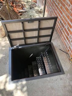 an open box sitting on the ground next to a brick wall