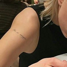 a woman with a small tattoo on her arm eating food at a table in a restaurant