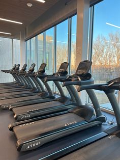 there are many treadmills lined up in the gym with windows looking out on the water