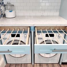 two washers are open in the middle of a kitchen with blue cabinets and white counter tops