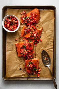 some food is laying out on a baking sheet with a spoon and bowl next to it