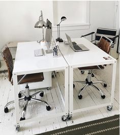 two white desks with chairs and a laptop on them in an empty room next to a window