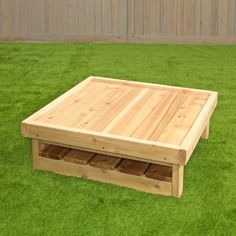 a wooden coffee table sitting on top of green grass