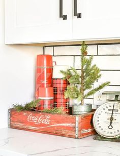 an old coca - cola crate with a christmas tree in it is sitting on a kitchen counter