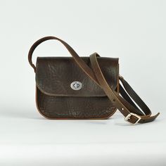 Our classic small cross body bag, crafted using rustic Brown leather. We love this small satchel style, and wanted to create a softer version, using the same supple, study, vegetable tanned leather which we use for our belts.  Measuring 19 x 15 x 5 cm, and with a strap adjustable between 128 and 137 cm, the vegetable tanning process beautifully preserves the organic past life of the material, creating a natural, characterful, finish, which will wear beautifully, taking on personality and charm with use.  Completed with a silver  finish turnlock closure for accessibility and security, the minimal design aims to be an easy every day accessory. Always lovingly handmade in our London workshop.  Recently we have created a small run of accessories using the robust Italian vegetable tanned leathe Brown Saddle Bag With Adjustable Strap For Everyday, Brown Textured Leather Flap Bag For Daily Use, Everyday Brown Saddle Satchel, Brown Waxed Finish Crossbody Satchel, Brown Textured Leather Saddle Crossbody Bag, Everyday Brown Shoulder Saddle Bag, Brown Waxed Saddle Bag For Everyday Use, Brown Textured Leather Crossbody Saddle Bag, Everyday Vintage Brown Satchel With Adjustable Strap