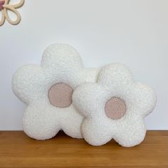 two white flowers sitting on top of a wooden table