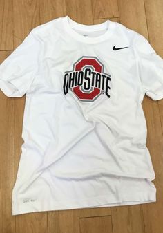 a white shirt with the word ohio state on it sitting on top of a wooden floor