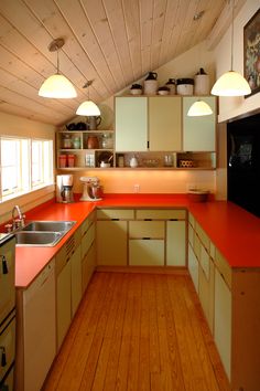 a kitchen with orange counter tops and wooden flooring in an attic style home,