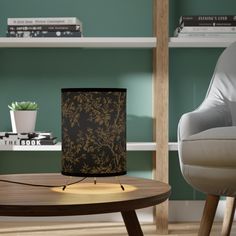 a table with a lamp sitting on top of it next to a chair and bookshelf