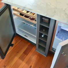 an open refrigerator door in a kitchen next to a counter top with drawers on both sides