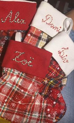 three red and white christmas stockings with personalized name tags on them, sitting next to each other