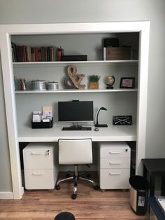 a white desk with two drawers and a computer monitor on it in front of a bookshelf