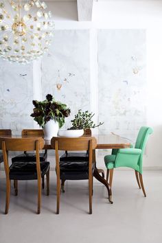 a dining room table with chairs and a vase filled with flowers sitting on top of it