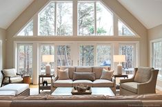 a living room filled with lots of furniture under a large skylight in front of windows