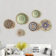 a living room filled with white furniture and lots of baskets hanging on the wall above it