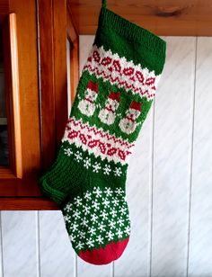 a green and red christmas stocking hanging from a wooden door frame on a wall