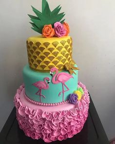 a three tiered cake decorated with pink, blue and yellow frosting flamingos