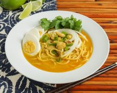 a white plate topped with noodles and an hard boiled egg next to chopsticks