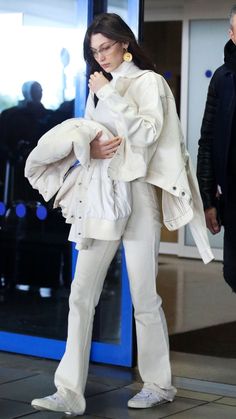 a woman in white is walking through an airport