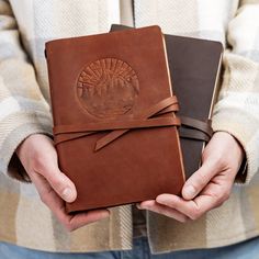 a man holding two leather journals in his hands