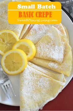 small batch lemon crepes on a white plate with powdered sugar and sliced lemons