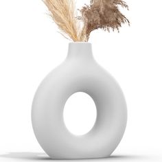 a white vase with some dried plants in it