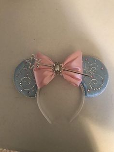 a minnie mouse ears headband with pink bow and pearls on the top, sitting on a table