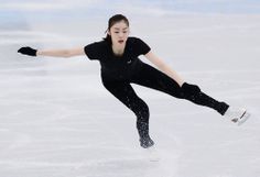 a woman skating on an ice rink wearing all black and white clothes with her arms outstretched