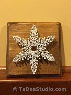 a snowflake made out of string on top of a wooden box