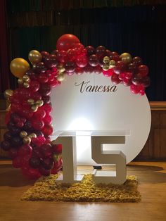 a large balloon arch with the number fifteen surrounded by red, gold and white balloons