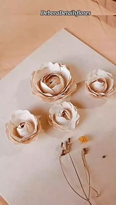 three paper flowers sitting on top of a piece of paper