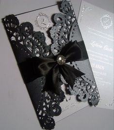 a black and white wedding card with a bow on it's side, next to an envelope