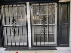 a window with iron bars on it and flowers in the window sill next to it