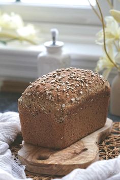 a loaf of bread sitting on top of a wooden cutting board next to a window